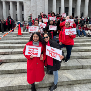 Housing and Homelessness Advocacy Day advocates from across the state of Washington gathered at the capitol steps in Olypia wearing iconic red scarves, as red is the color of homelessness and housing advocacy. Signs they hold read, "Everyone needs a home" and "Rent Stabilization Yes!)