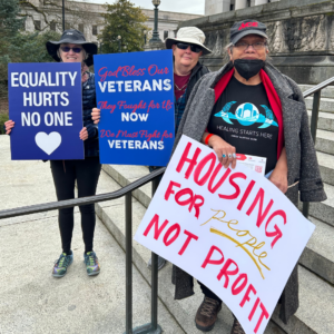 Advocates hold signs in support of veterans and equality within housing justice, in Washington state at Housing and Homelessness Advocacy Day 2025.